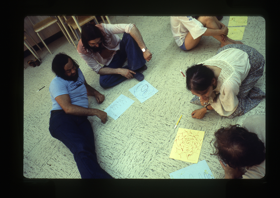 Des participants au 7e congrès d’expression dramatique sont assis par terre et écrivent sur des feuilles de papier, 1978. / Photographe inconnu. 1 photographie : diapositive coul. Archives UdeM, P0419-K-3-D0006