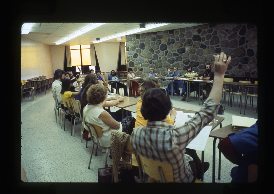 Des participants au 7e congrès d’expression dramatique sont assis dans une salle de classe. 1978. / Photographe inconnu. 1 photographie : diapositive coul. Archives UdeM, P0419-K-3-D0006