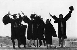 Six finissants heureux sautent en chœur lors de la collation des grades, vêtus de toges et diplômes à la main, [1975]. Studio Desautels. D00371fp08222.